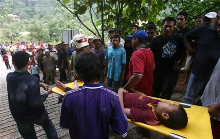 People carry an orphan injured in a landslide in Hulu Langat in central Selangor state, outside Kuala Lumpur, Malaysia, Saturday, May 21, 2011. Police say about 30 children were buried by the landslide that hit an orphanage Saturday. (AP Photo) MALAYSIA OUT
